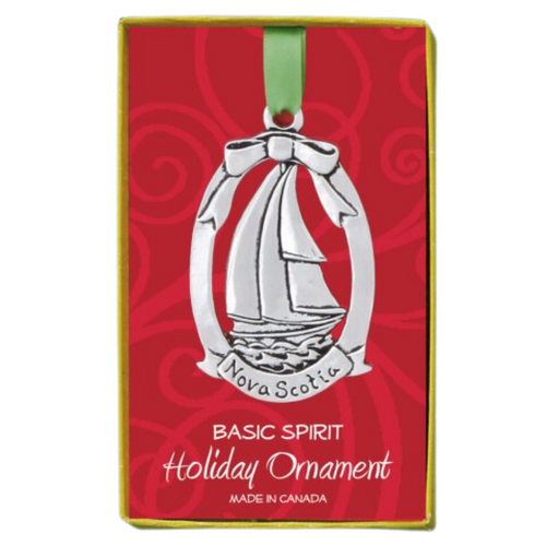 Shows a gift box holding an oval ornament made of pewter. Inside the oval is the shape of a sailboat/Schooner, with a bow at the top, and Nova Scotia written at the bottom. 